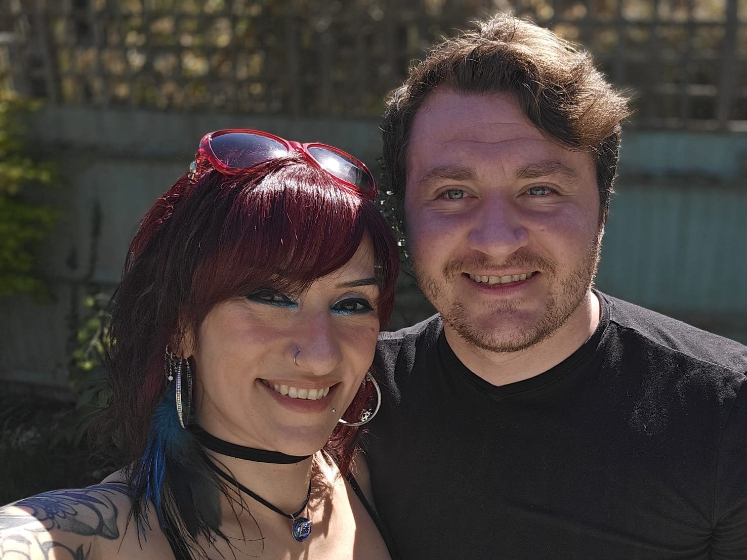 athena-raven-joseph-alai-couple-photo Athena Raven, with reddish-purple highlights in her hair, and Joseph Alai smiling together outdoors.